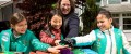 Junior Girl Scouts and a volunteer with hands in center. image description unavailable