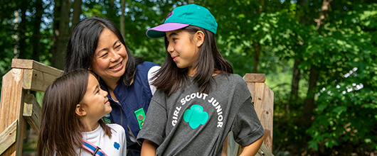 A Girl Scout volunteer smiling at a Junior and Daisy Girl Scout.
