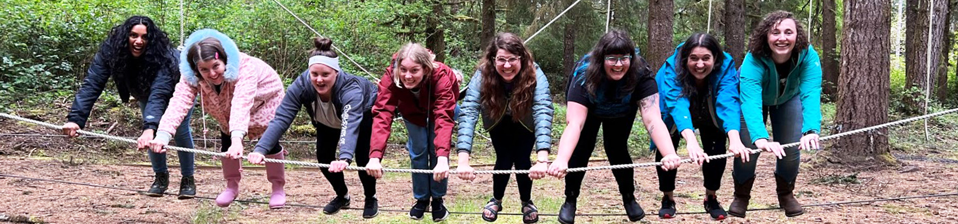  GSOSW staff smiling while balancing on a ropes course element 