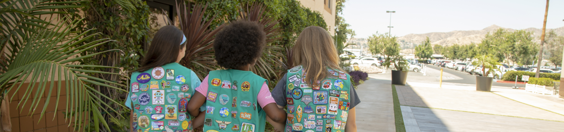  A group of Junior Girl Scouts with fun patches on back of uniforms walking together 