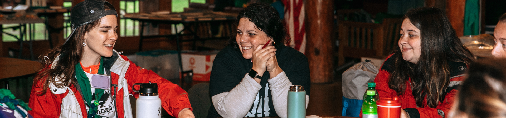  three adult girl scout volunteers sitting together smiling laughing 